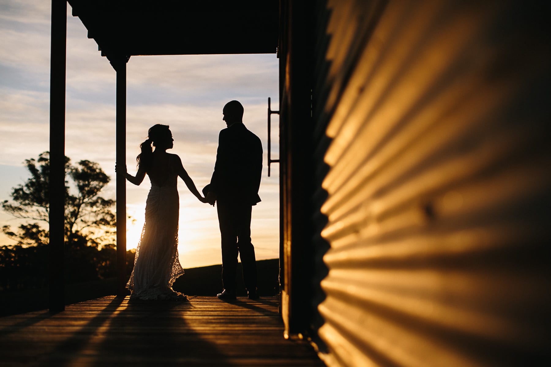 Photograph of bride and groom holding hands after their wedding and watching the sunset over Mali Brae Farm, Southern Highlands NSW.