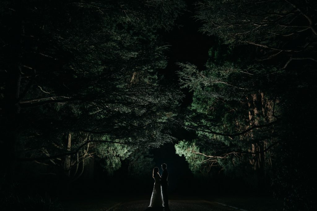 wedding photograph featuring a creative silhouette of the bride and groom standing hidden in a lit forest at Bendooley estate
