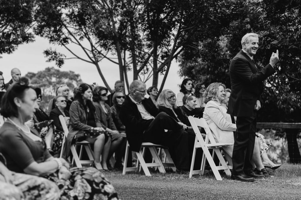 Black and white wedding photo of the wedding guests, father standing in the front and showing the bridal couple the finger at Jaspers Berry