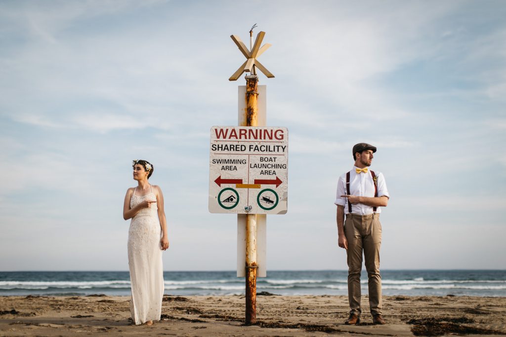 Berry; South Coast Wedding photographer; Photograph of bride and groom pointing to a warning sign on the beach