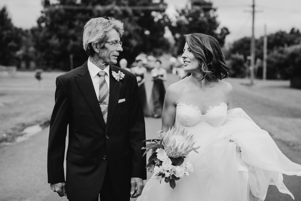 Black and white portarit of father talking to his daughter, the bride, walking to her Berry wedding