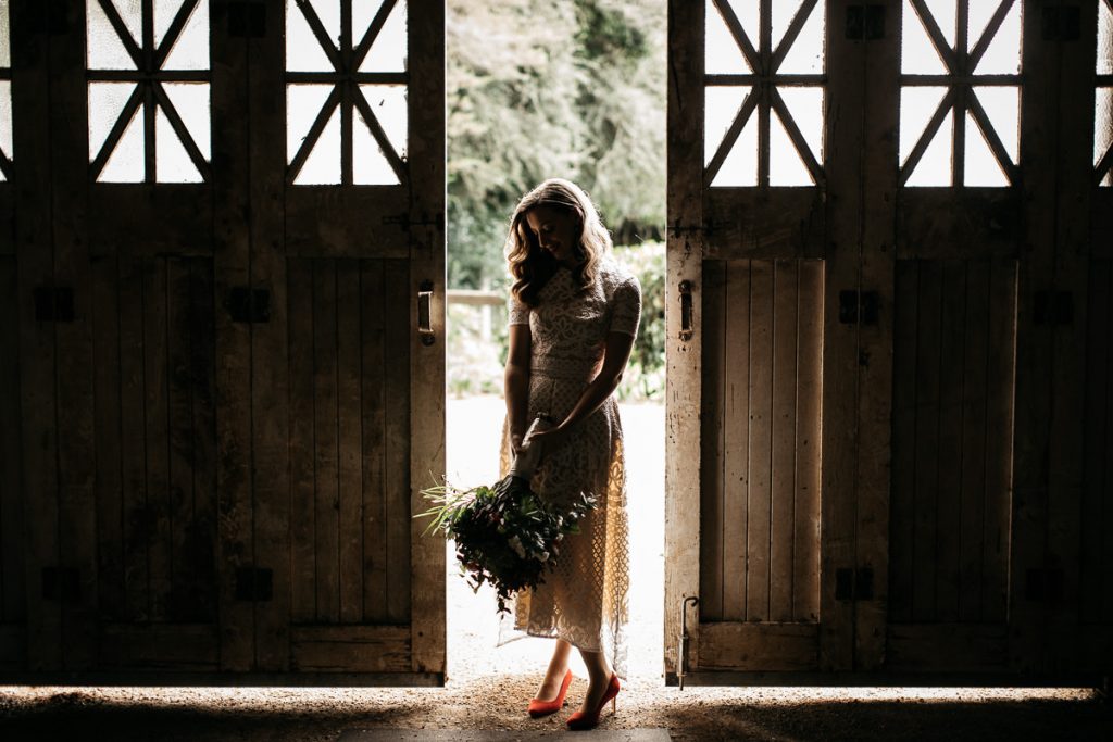 Southern Highlands Wedding Photography: Sherry poses between the barn doors at her wedding venue in Bowral, in the Southern Highlands