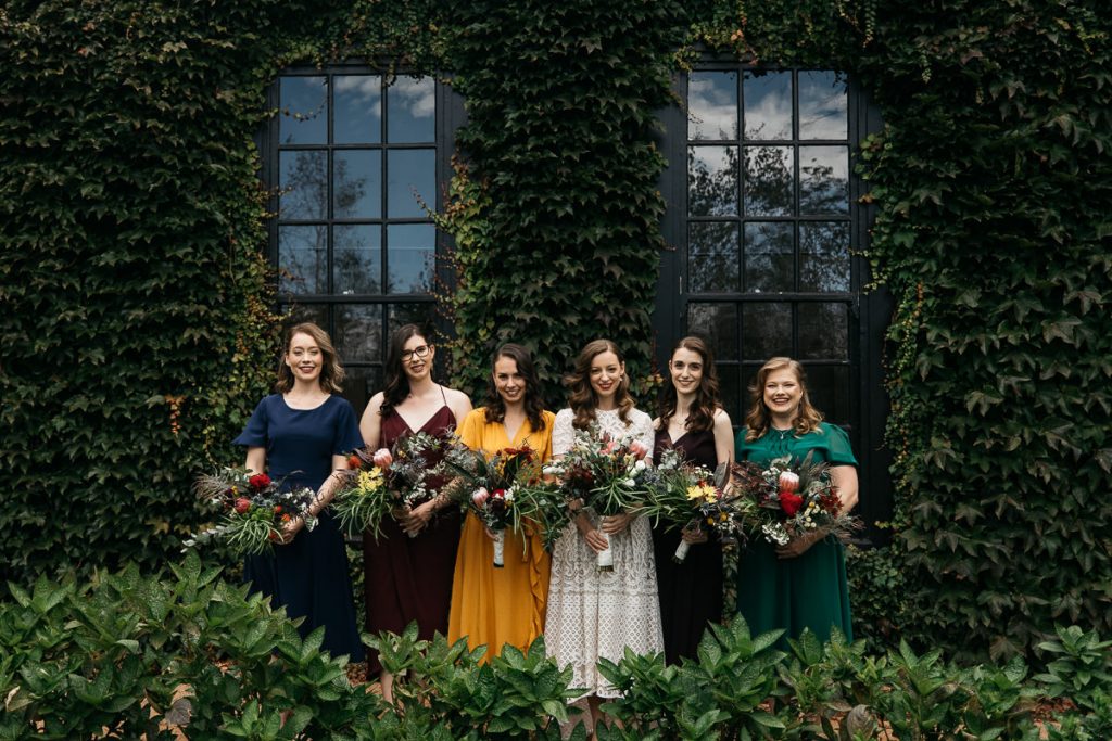 The bride and briesmaids show off their dresses in front of the wedding venue in Bowral