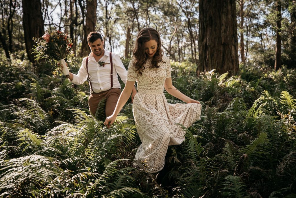 Bride and groom wander laughingly through ferns at their Bowlral wedding in the southern highlands