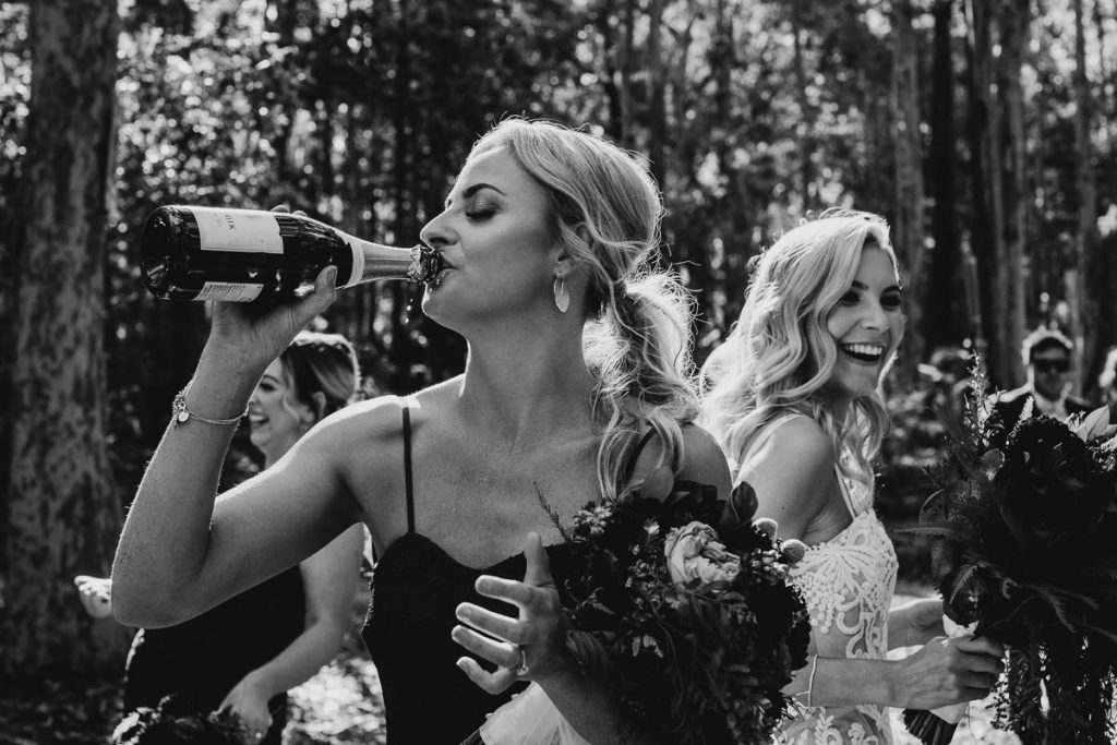 Photograph of a wedding guest downs a bottle of champaign at a wedding in Bundanon on the South Coast