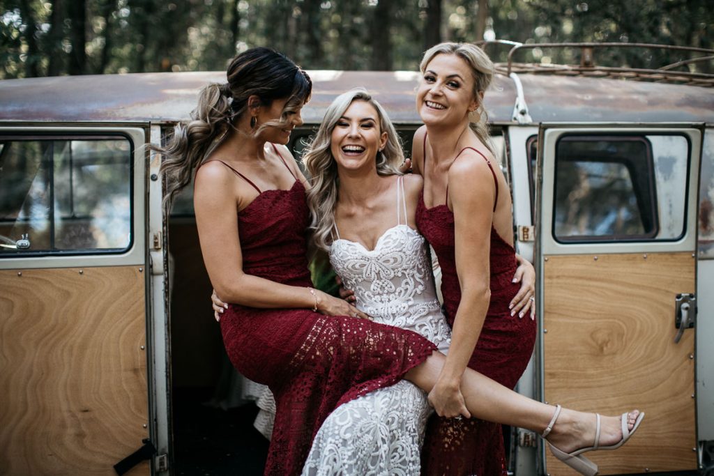Bride in a fun pose with her two bridemaids laughing in front of a caravan at a Bundanon Wediing on the South Coast