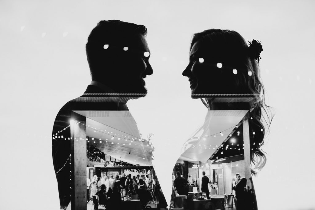 Creative black and white wedding photograph with silhouette of bride and groom reflecting another image of the wedding venue in Bundanon