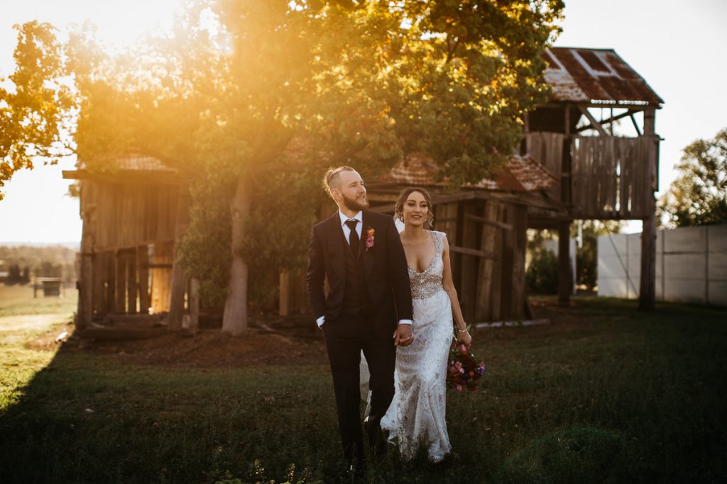 Wedding couple walking towards the photographer with a rustic falling-down shed in the background at Burnham Grove Wedding venue