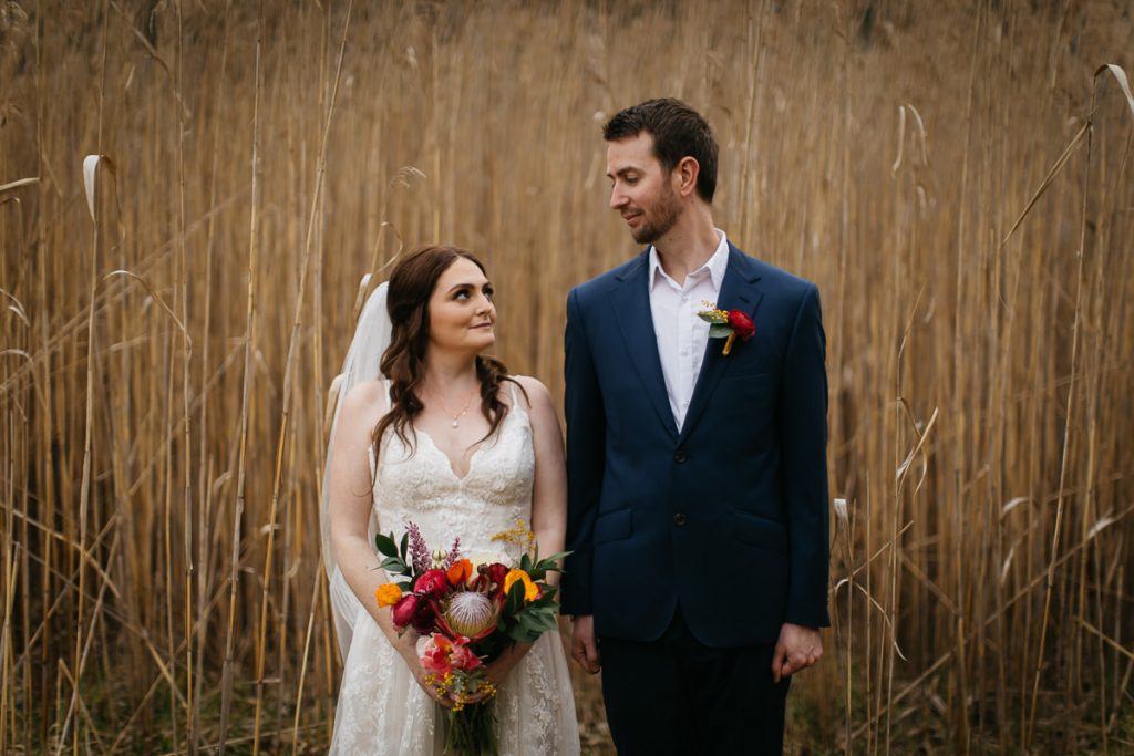 Bride and groom lovingly look at each other in a wheat field at their Butter Factory Wedding