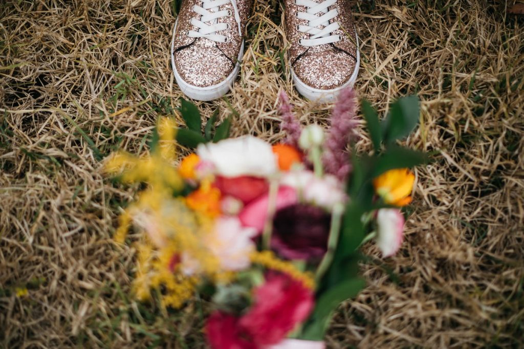 Blurry boquet on the ground in front of sparkly converse shoes; Butter Factory Wedding photography