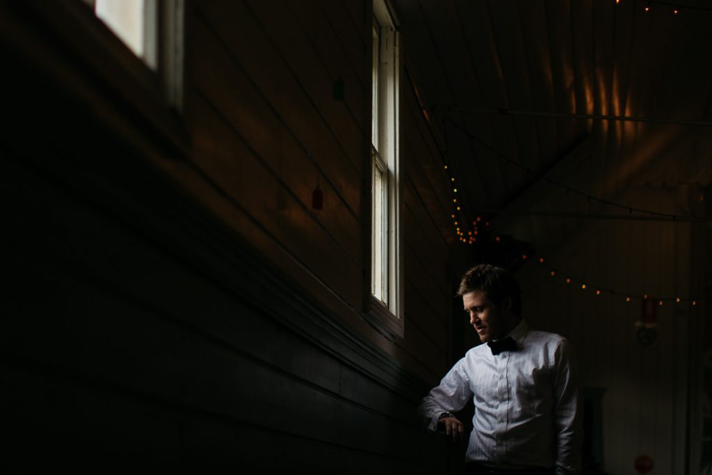 Groom looks at his watch by the light of a window at his Canberra country-style wedding