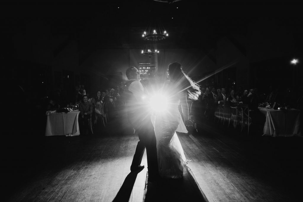 Black and white wedding photo of bride and groom dancing with the spotlight shining between them at their Centennial Vienyards Wedding in Bowral