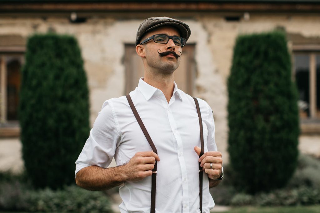 Groomsman proudly struts his braces for the photographer at a Cupitts Winery Wedding