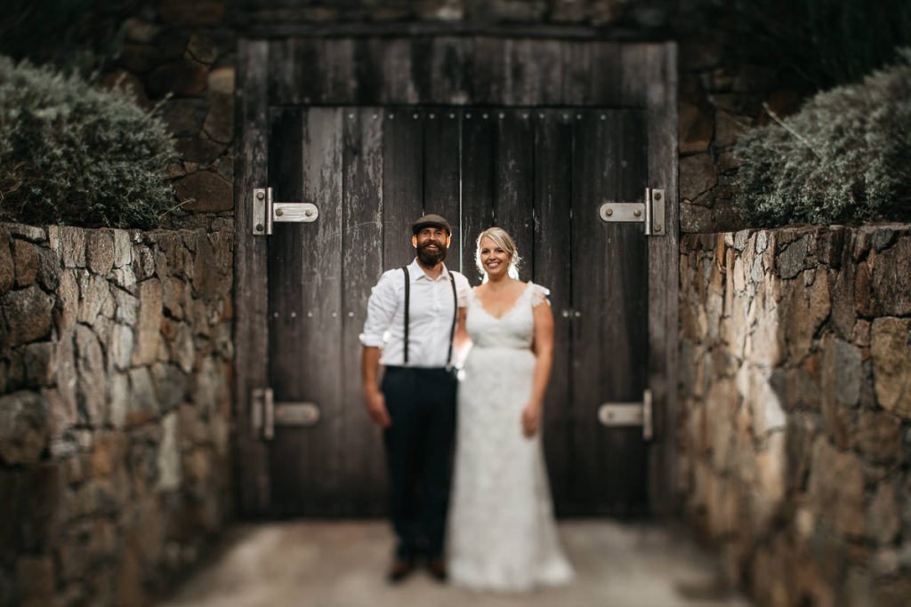 rustic photograph of bride and groom standing in front of a barn door at their Cupitts Winery Wedding