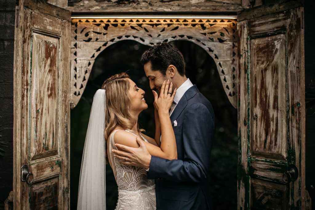 Couple lovingly touch each others face and arms in a rustic wooden doorway at their Jaspers Berry wedding
