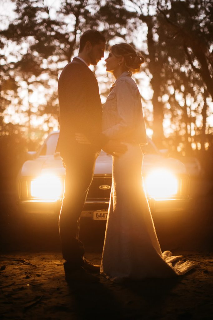 bride and groom look at each other lovingly in front of the headights of their car; Kangaroo Valley Bush retreat; South Coast Wedding Photographer