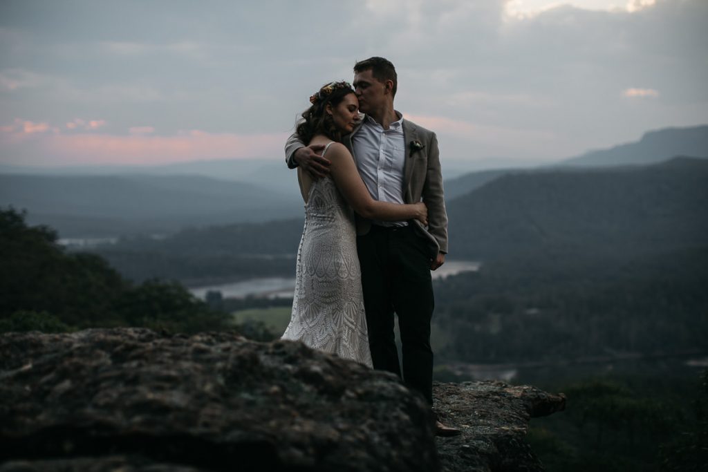 Bride and groom lovingly hold each other on the mountain top overlooking the valley - Kangaroo Valley Bush Retreat Wedding Photography