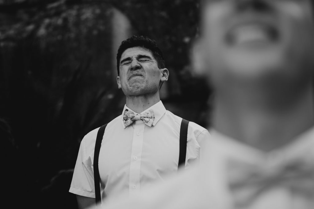 Black and white image of a groom pulling a face at his Kangaroo Valley Busg Retreat Wedding; Wedding photography South Coast