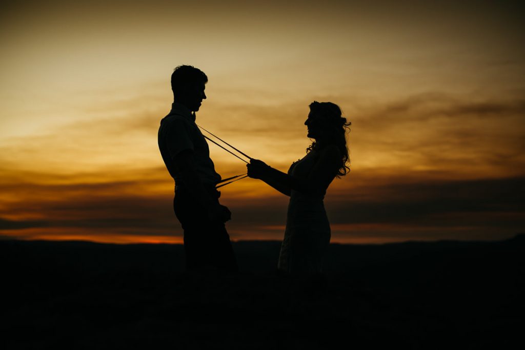 Fun sunset silhouette of bride holding groom by his braces; Kangaroo Valley Bush Retreat Wedding Photographer South Coast
