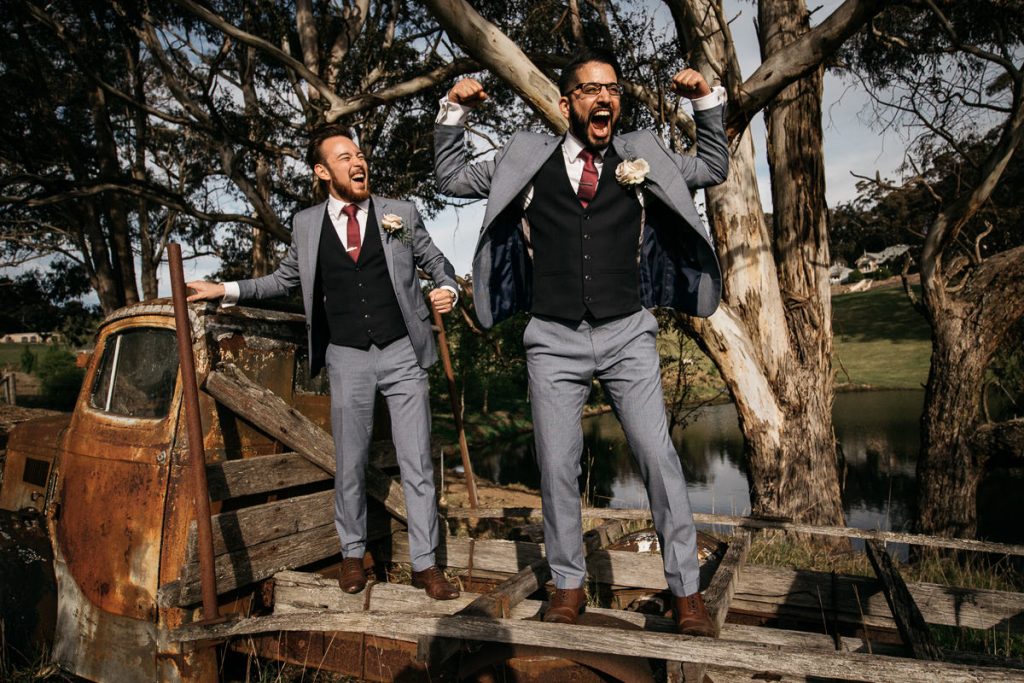 groom and best man stand cheering on a rust truck at his Marlie Brae Wedding in the Southern Highlands; Wedding Photographer