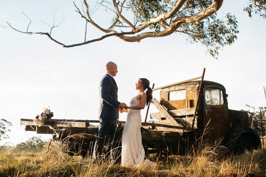 Bride and groom hold hands in front of a rusty truck at their Marlie Brae Farm Wedding; Southern Highlands Wedding Photographer