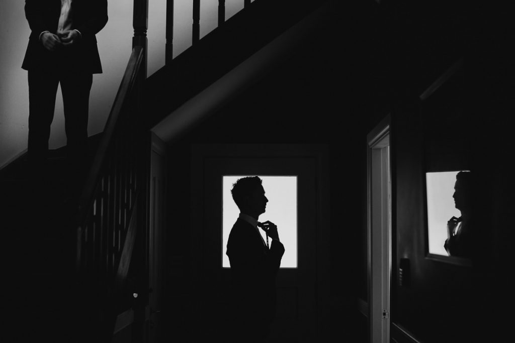 Silhouette of groom tying his bowtie before his wedding at Melross in the Kangaroo Valley, Kangaroo Valley Wedding Photography