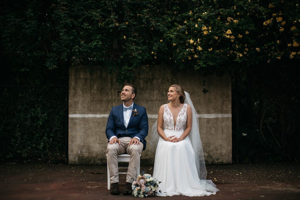 Bride and groom sitting, looking up at the sky; Merribee - South Coast Wedding Photographer