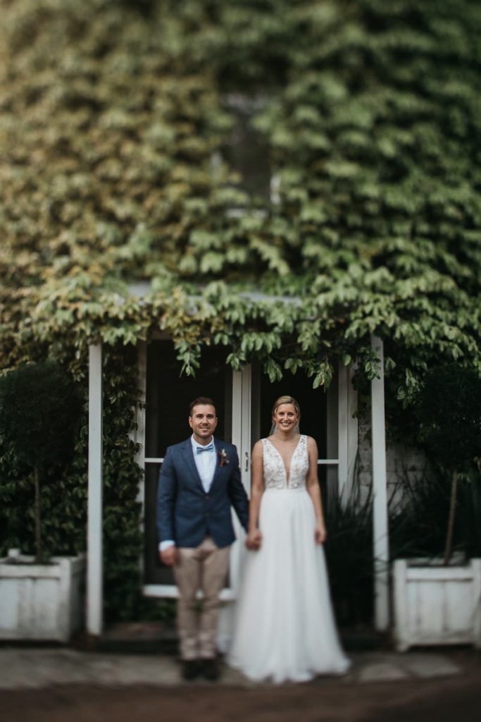 Bridal couple standing in the closed doorway of their leafy wedding venue in Merribee on the South Coast