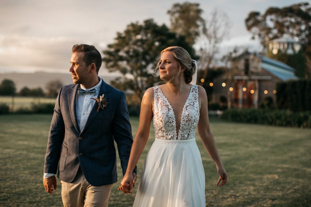 Bride and groom walk holding hands at their Merribee wedding on the south coast; wedding photographer