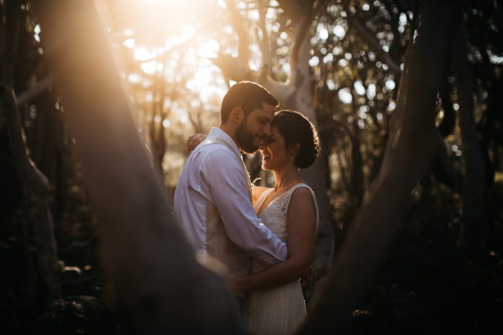 Bride and groom hug amongst the trees at their Paperbark Camp Wedding; South Coast Wedding Photographer