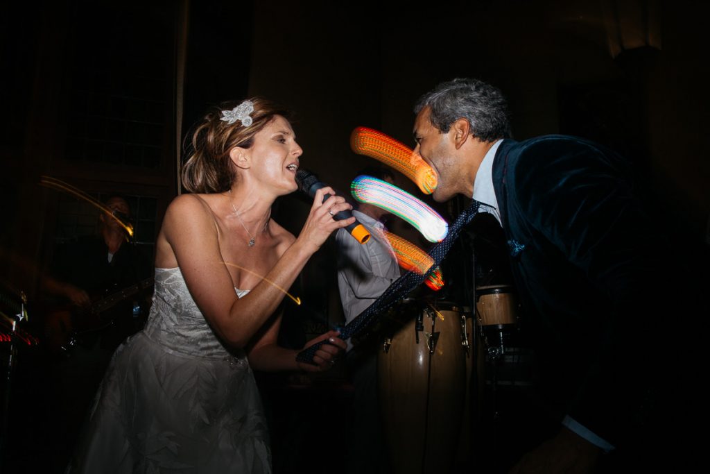 Bride signs to the groom while holding him by the neck tie; Papers Wedding Photographer Southern Highlands