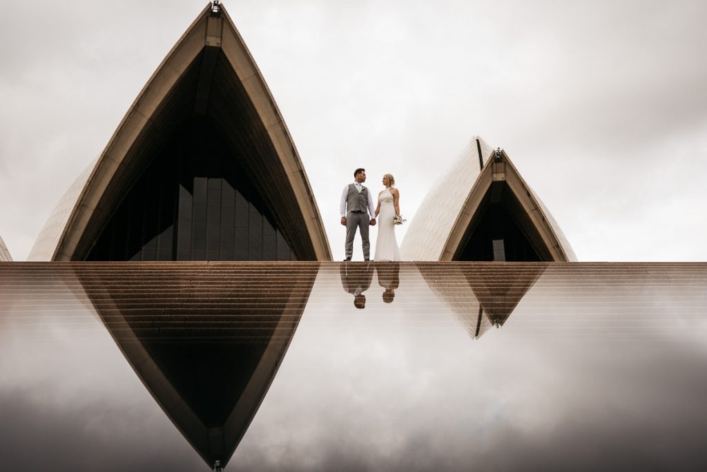 Wedding couple pose between reflecting towers of the Sydney Opera House; Sydney Wedding Photography