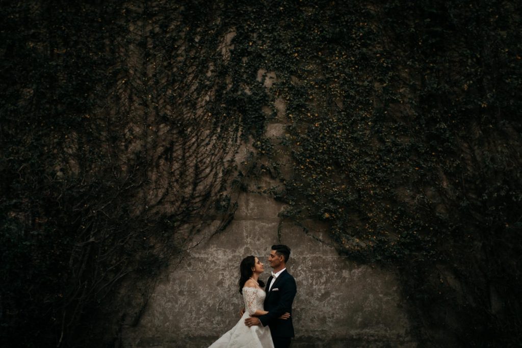 Sydney Wedding photographer; wedding couple stare into each others eyes in front of a wall covered in plants