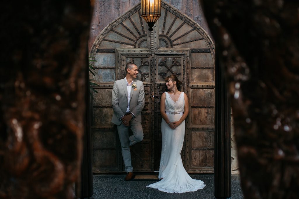 Bride and groom pose in front of an ornate doorway in the Whitsunday Wedding Photographer