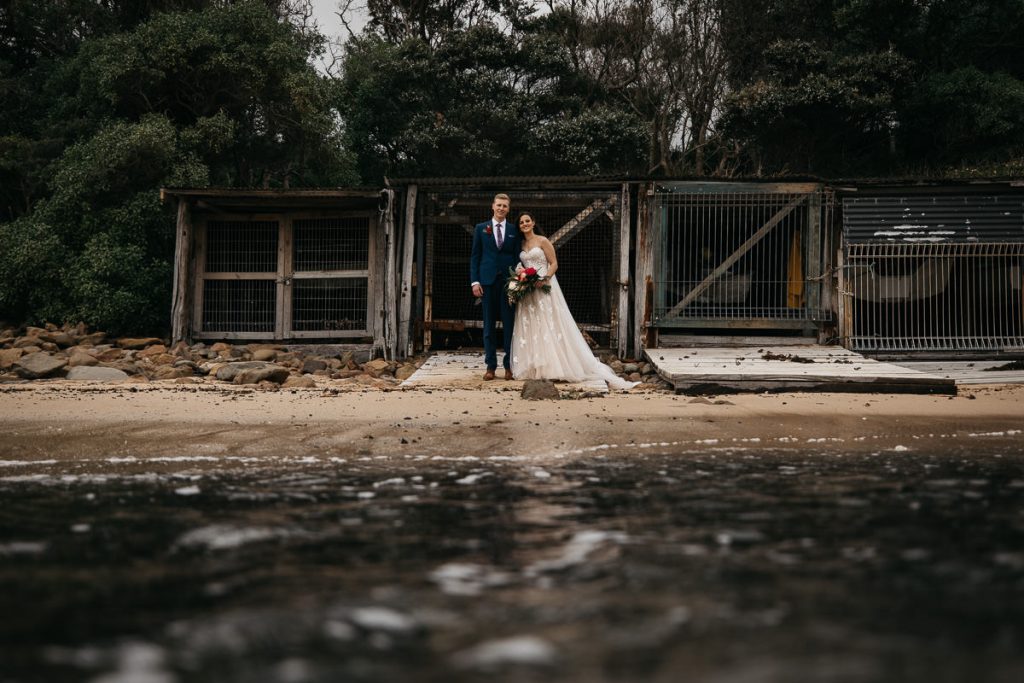 Wollongong Wedding Photographer; Bride and groom pose in front of cages on the beach in Wollongong