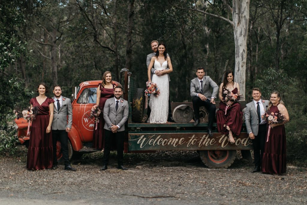 Bridal party pose on truck saying 'Welcome to the Woods' at a Woods Farm Wedding; South Coast Wedding photography