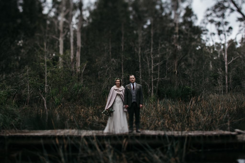 Bride and groom stand infront of the forest; Worrowing South Coast Wedding Photographer